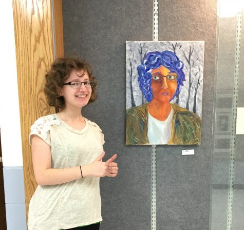 Junior Julia Kupperman poses next to a self-portrait she painted.