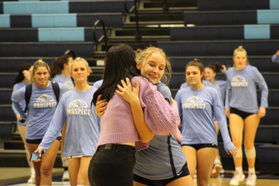 Freshman Alli Linke hugs head coach Miles after the last JV game win. Varsity starts to walk on the court for their game.