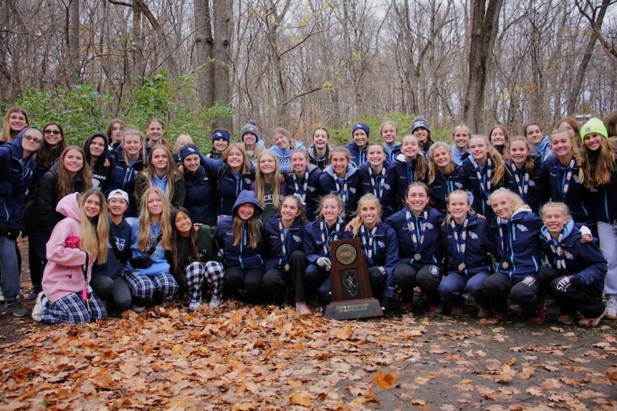 The entire girls cross country program crowds around the first place trophy.