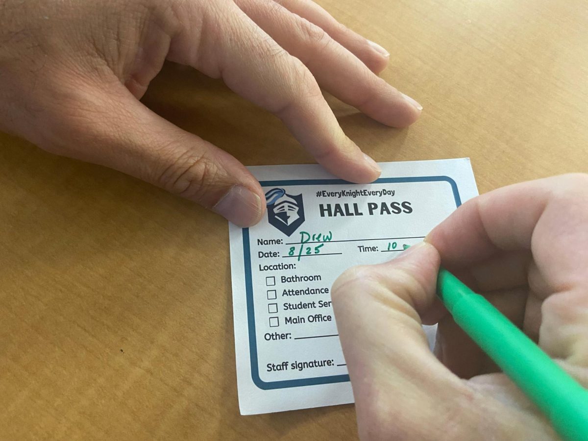 Student writing their name on the now mandatory bathroom passes. Photo courtesy of Xander Adkins