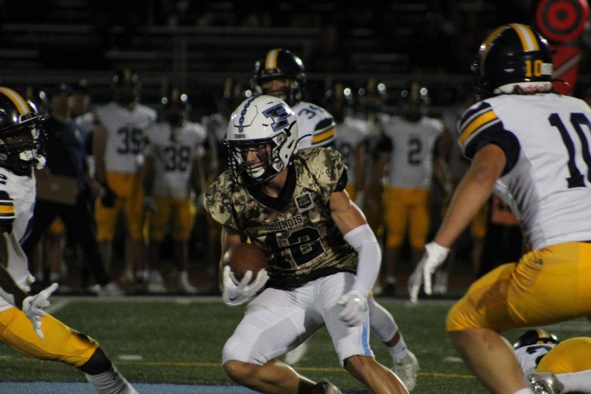 Junior Nicky Carlucci runs with the ball, avoiding the Glenbrook South defense.