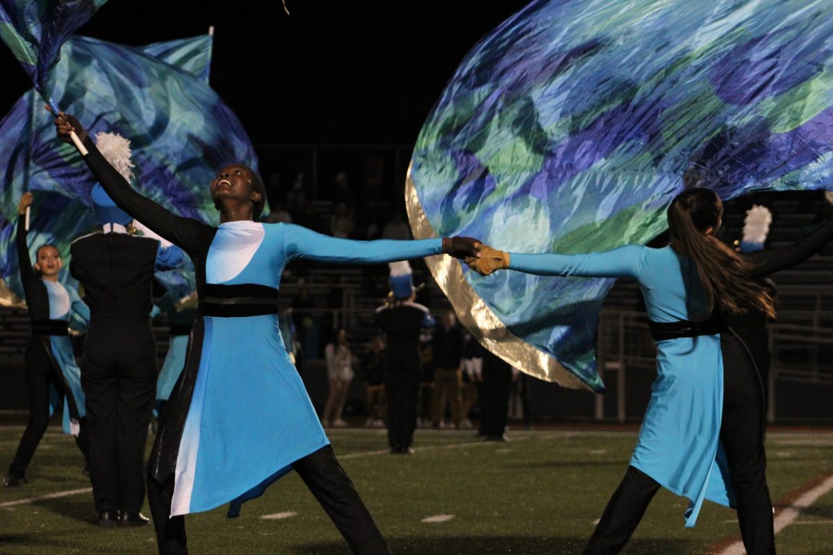 Flag in the air, senior Posi Sulaimon connects hands with her “guardmate” during the performance.