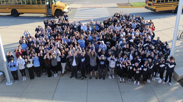 Students who volunteered at Prospect Gives Back pose in front of the school holding up The U. (Photo by Mollie Kearns)