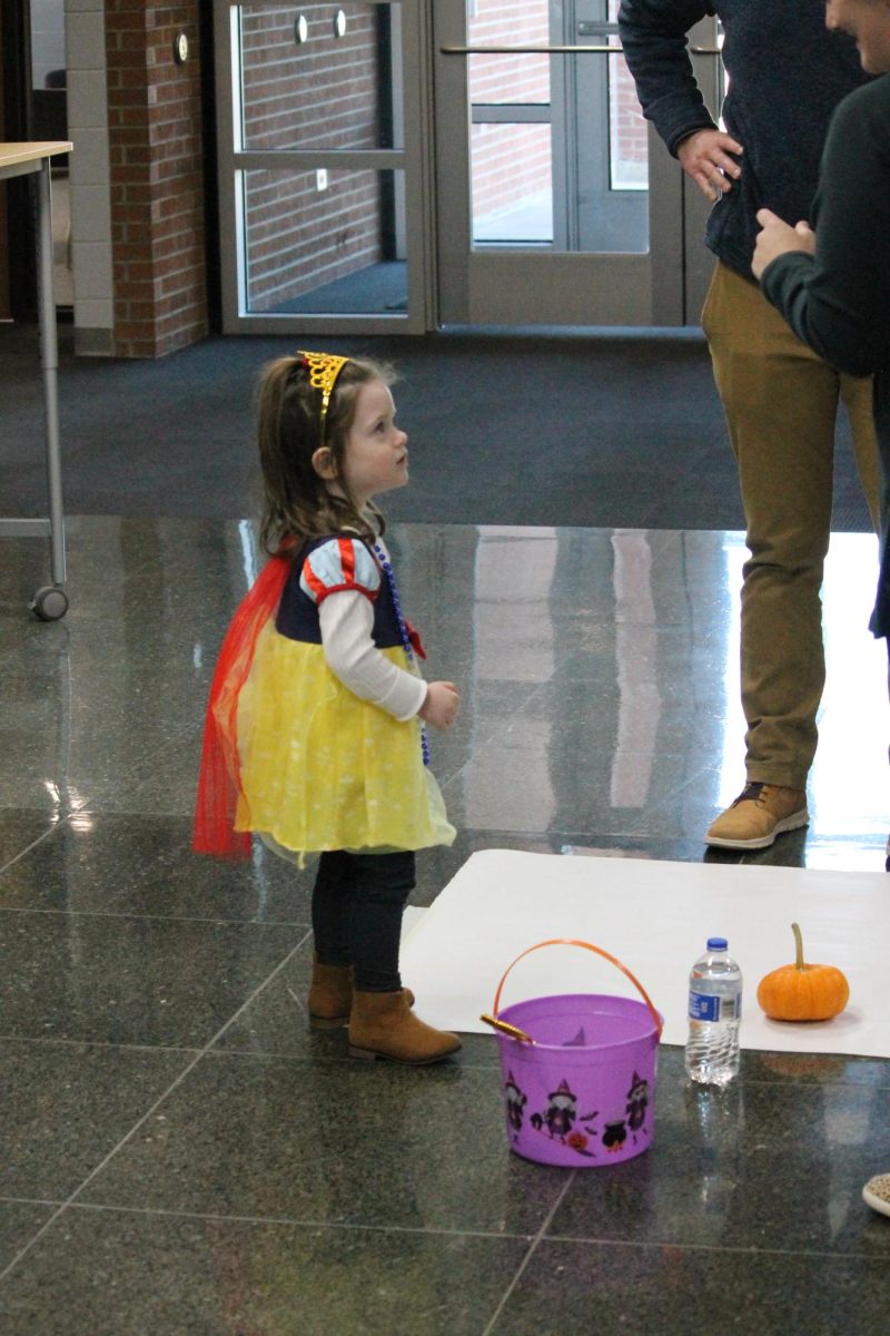 Young girl dressed up as Snow White talking to volunteers.