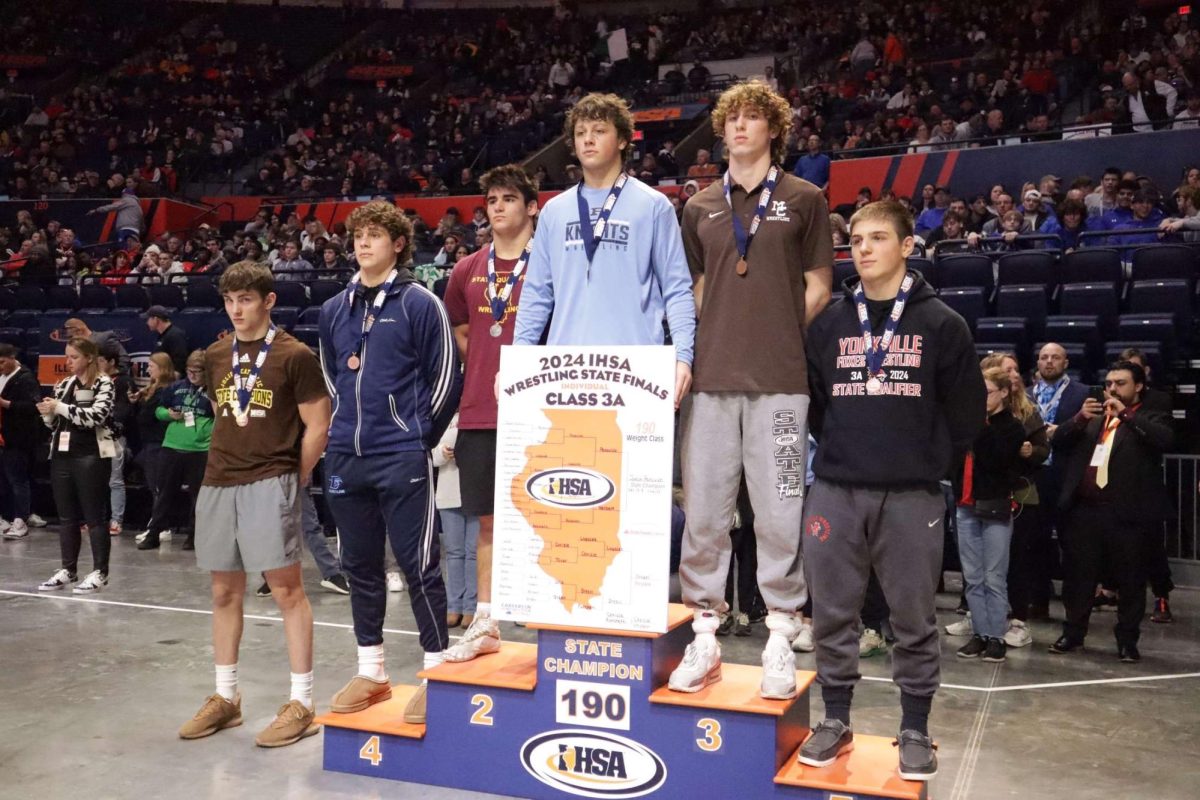 Sophomore Jaxon Penovich stands in first place on the podium on Feb. 16. Holding the IHSA bracket in hand, Penovich lays claim to his outstanding 47-3 season — an improvement from his freshman year where he finished in fifth place at state with a record of 41-5. 