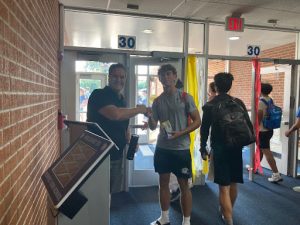 Former English teacher Erik Hammerstrom fist pumps senior Nick Carlucci as he says goodbye to students at the end of the school day. Hammerstrom enjoys his new job as a security guard because he gets to see familiar faces. 