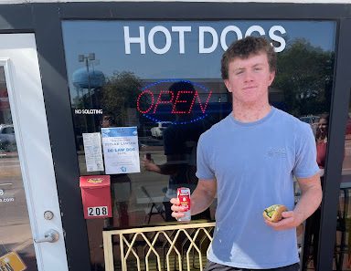 Hot dog! Senior Declan Lawlor stands in front of Hubby’s Dog House holding the new De-Law Dog.