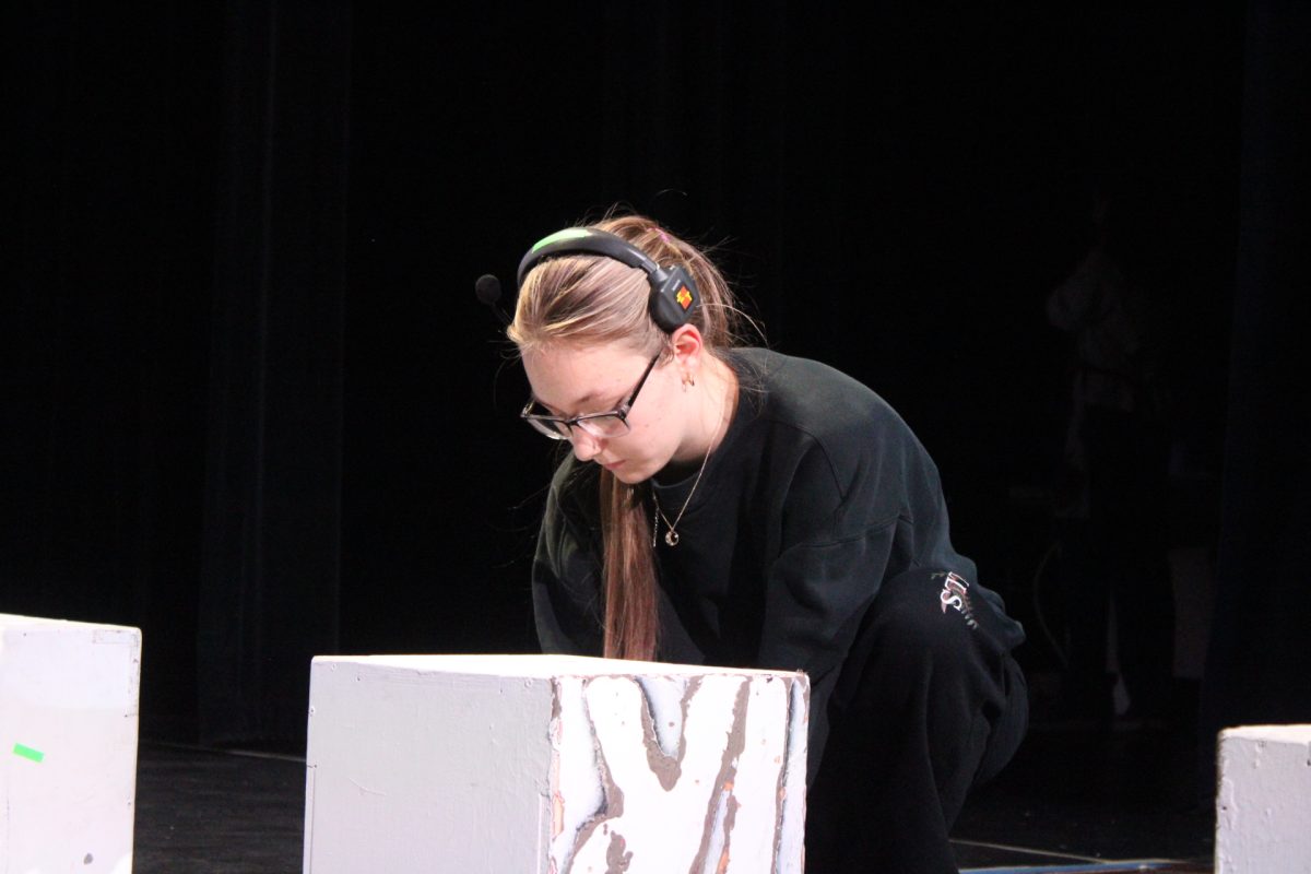 Senior tech leader Tori Kurchiy spike tapes prop boxes before the show.