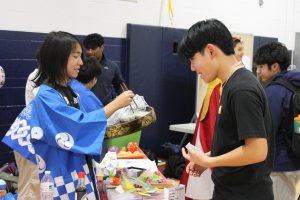 Freshman Shion Otsuka uses chopsticks to hand out sushi at the Japan table. 