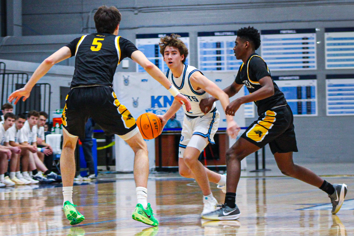 Junior Colin Tucker spots a gap between Metea Valley senior Jake Nosek (left) and junior Tre Watkins (right) as the two try to guard him during Prospect’s senior night matchup against Metea Valley.