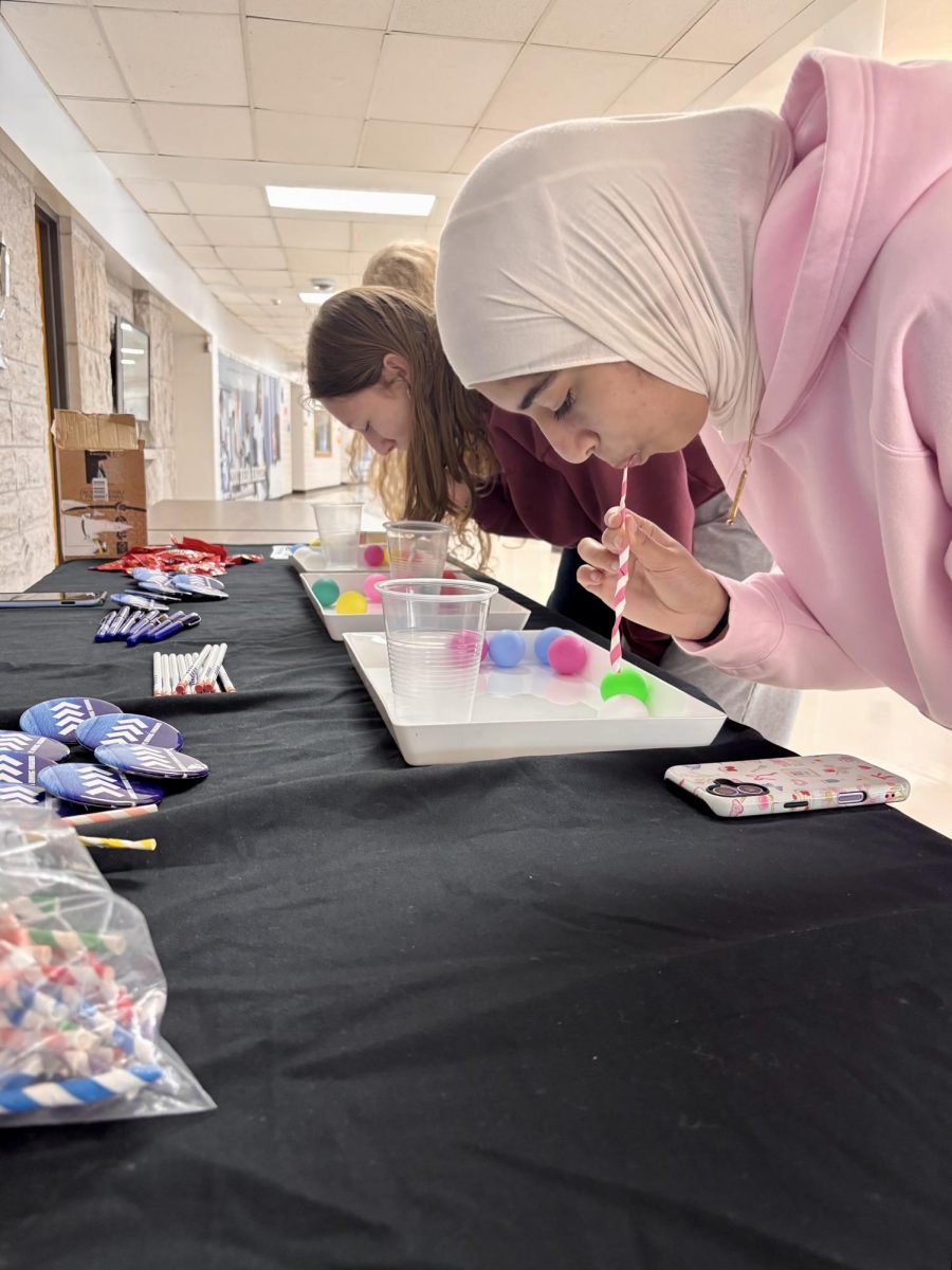 Students attempt to move the ping pong ball from the tray to the cup with a crumbled up straw. (photo by Tessa Trylovich)