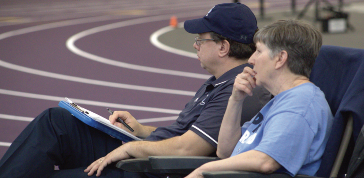 OBSERVING: Volunteer coach Tim Raub watches the pole vault with his mother Judy Raub during the girls’ track meet at the Rockton Hononegah Invite on Feb. 21. Raub is a volunteer coach for Prospect, which means that he isn’t paid for his time spent with the team.